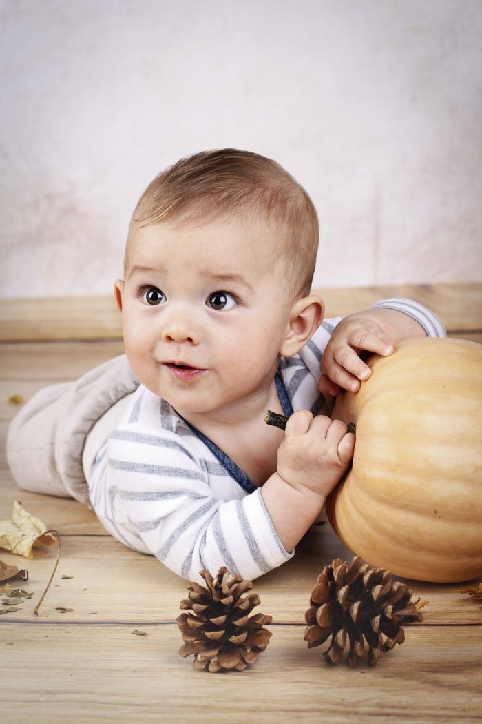 Baby boy with pumpkin and pine cones