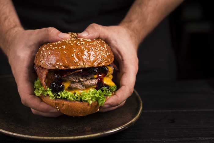 Hamburger held by hands on a plate