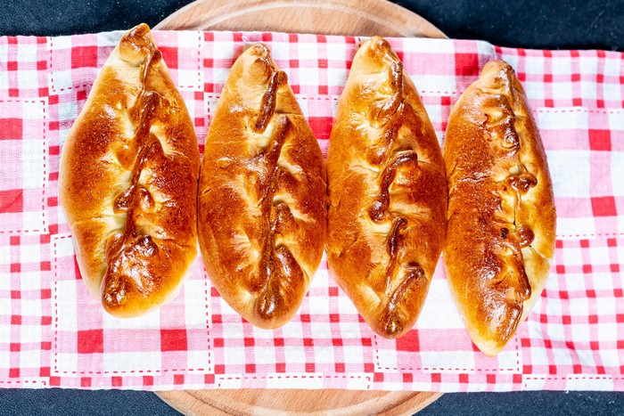 Four golden-brown pastries on a red and white checkered cloth