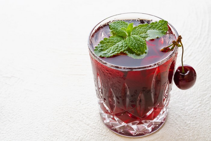 Cherry juice with mint and cherry garnish in a glass