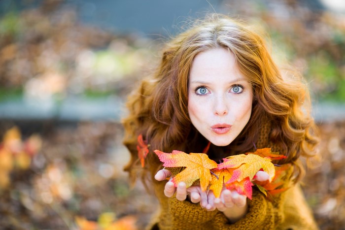 Woman with red hair holding autumn leaves