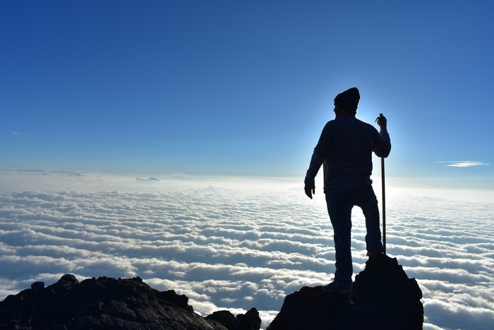 Climber on a mountaintop above clouds