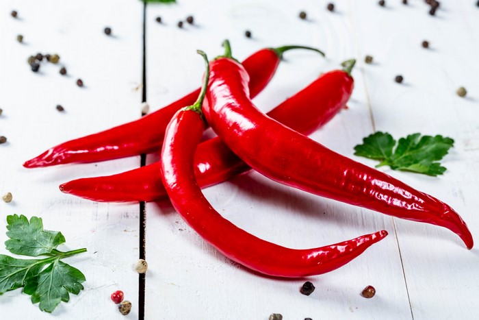 Red Chili Peppers and Peppercorns on White Wood
