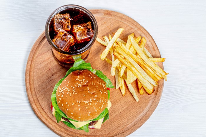 Hamburger, French fries, and Coca-Cola on a cutting board