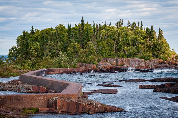 Concrete structure on rocky shore with forest background