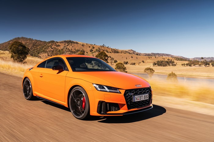 Orange Audi TT RS Coupe driving on a road