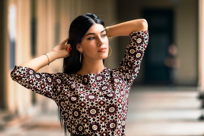 Brunette woman in floral dress posing with hands behind head