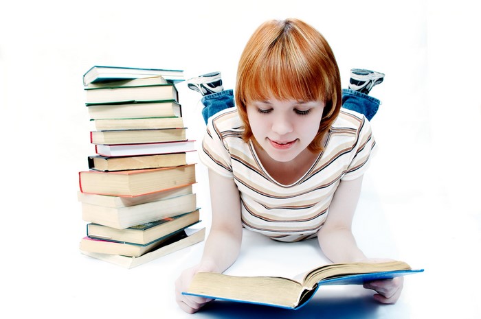 Young Girl Reading Book with Stack of Books
