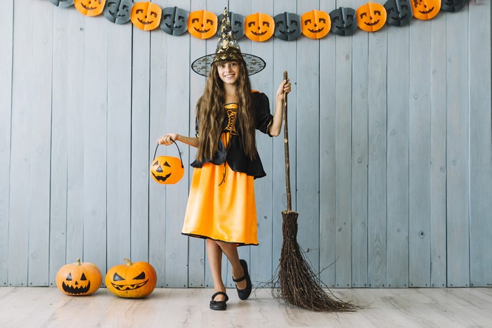 Girl in Witch Costume with Pumpkin Bucket and Broom
