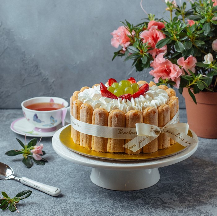 Charlotte cake with strawberries and grapes on a cake stand