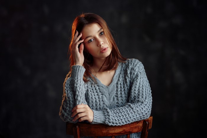 Young woman in a knitted sweater sitting on a chair