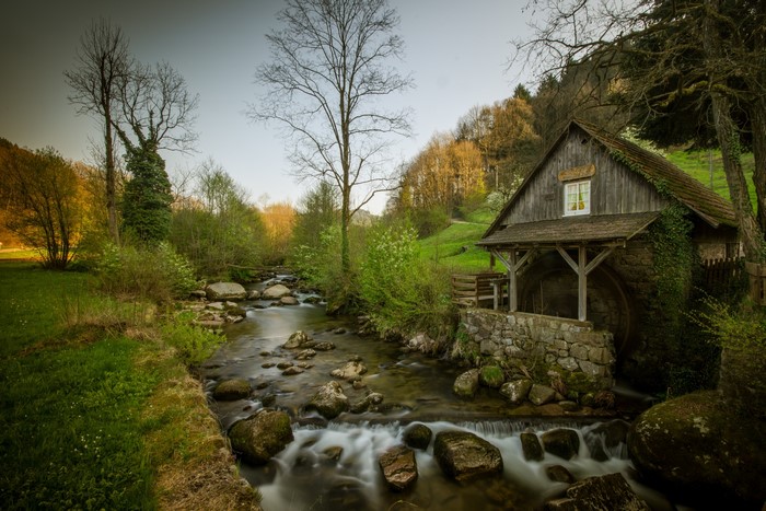 Watermill by a rocky river in a forest
