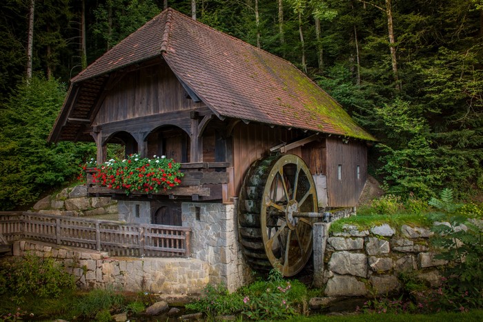 Wooden watermill with a large wheel in a forest