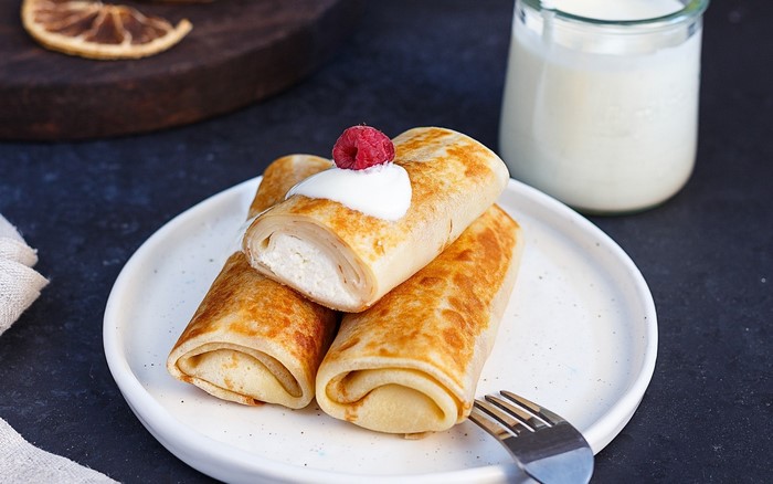 Rolled pancakes with cream and raspberry