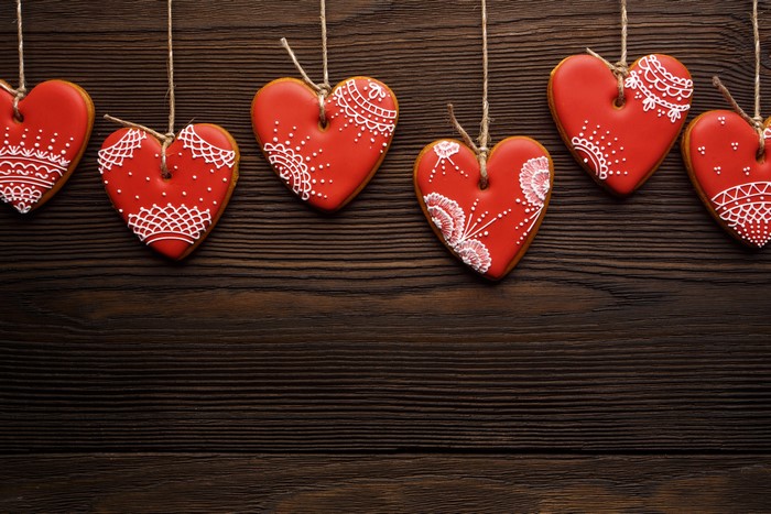Red heart cookies with white icing on wooden background