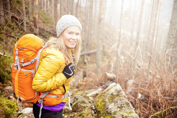 Blonde woman with backpack hiking in forest