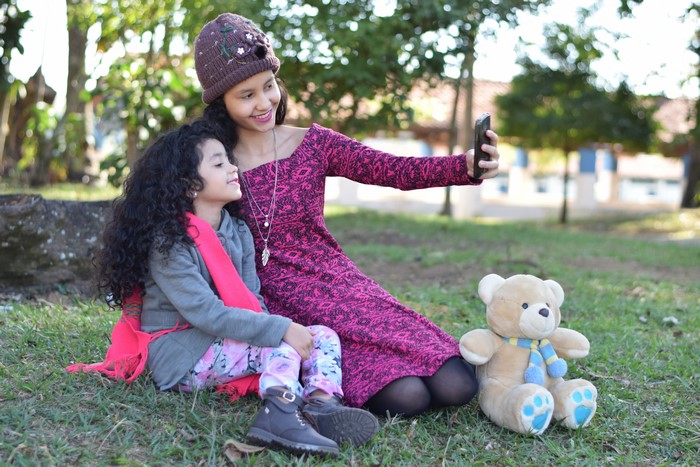 Two girls taking a selfie with a teddy bear