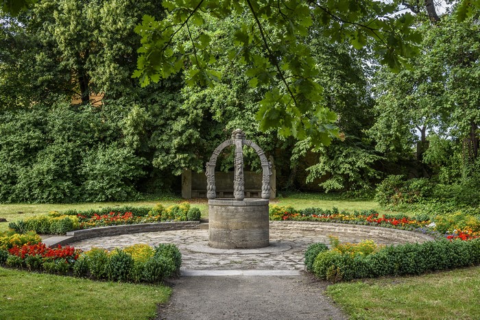 Stone well in a park with flower beds in Lutherstadt Wittenberg, Germany