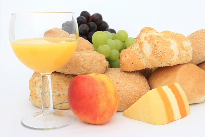 Glass of orange juice with bread, fruit, and cheese