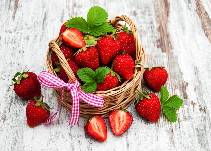Strawberries in a wicker basket with a pink ribbon