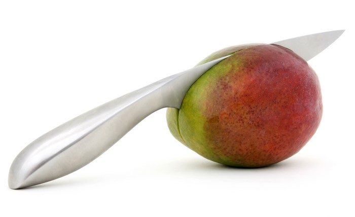 Knife cutting a ripe mango on a white background
