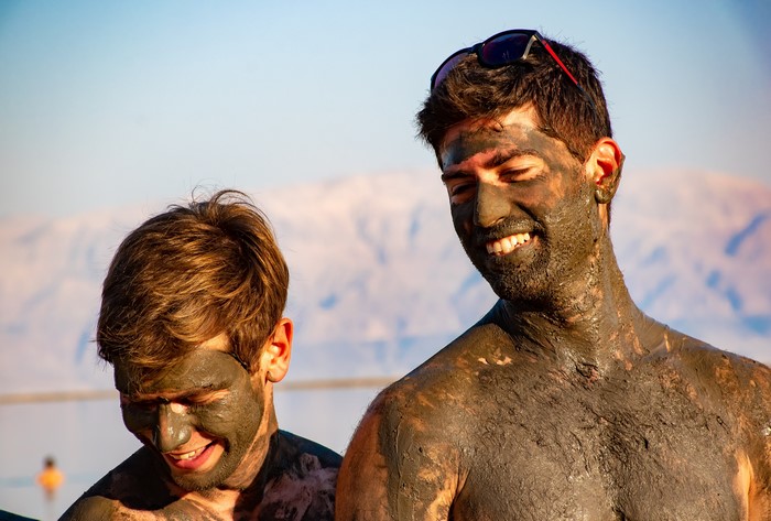 Two men covered in mud smiling