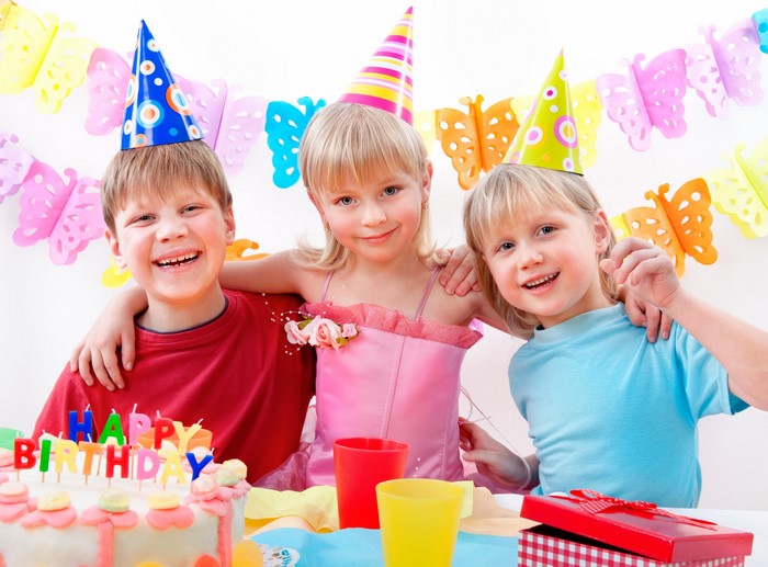 Children celebrating a birthday with cake and hats
