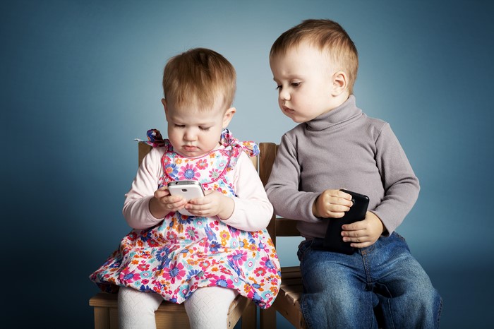 Two toddlers looking at smartphones