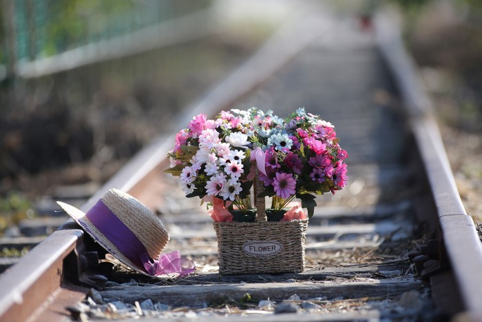 Bouquet of flowers and hat on railroad tracks