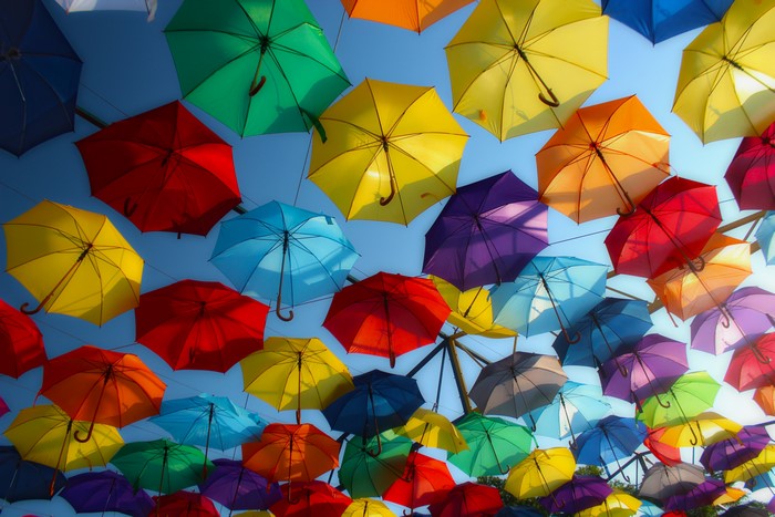 Many colorful umbrellas hanging in the sky