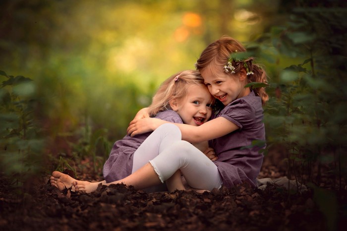Two little girls hugging in a forest