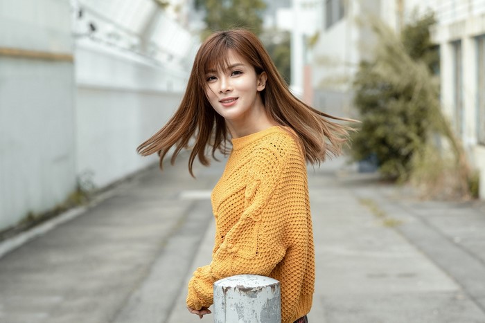 Young Woman in Yellow Sweater Smiling Outdoors
