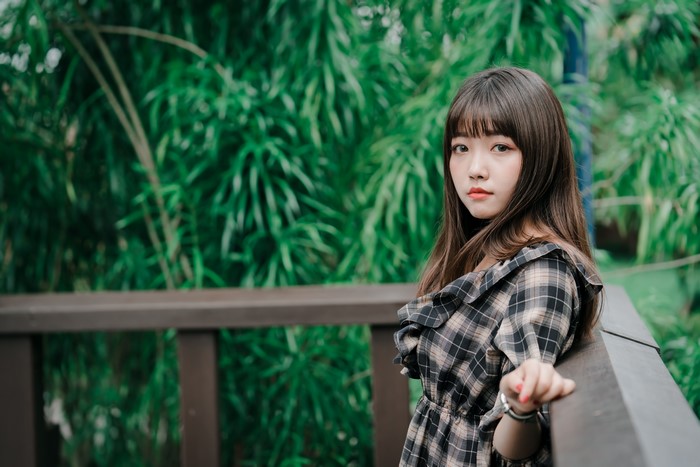 Asian girl in plaid dress on a wooden balcony