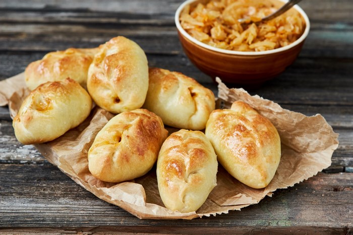 Golden baked buns with cabbage filling on parchment paper
