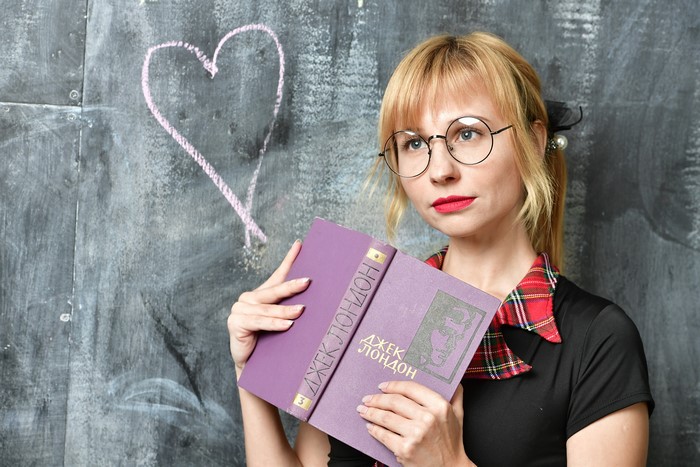 Blonde girl with glasses holding a book