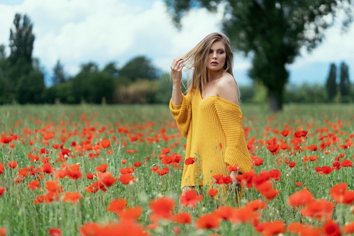 Woman in yellow sweater in poppy field