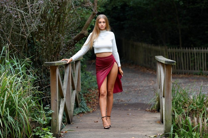 Woman in white top and red skirt on a wooden bridge