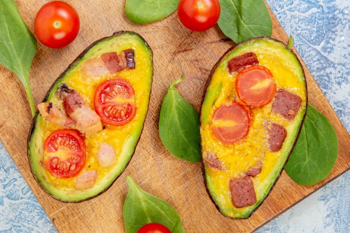 Baked Avocados with Tomatoes and Bacon on Cutting Board
