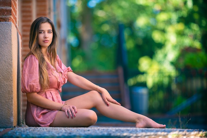 Young Woman Sitting in Pink Dress with Bokeh Background