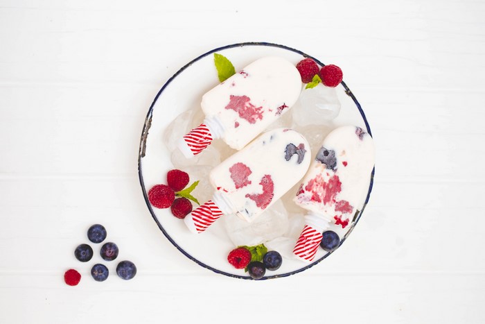 Three berry popsicles on a plate with ice