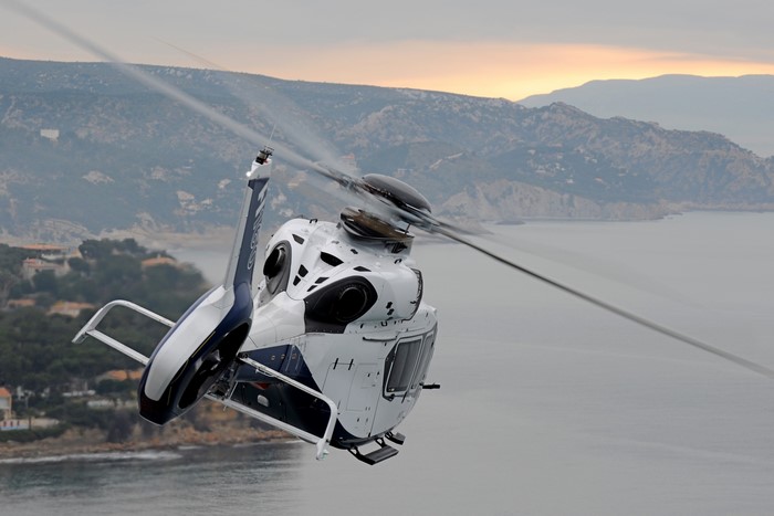 Airbus H160 helicopter in flight over a coastline