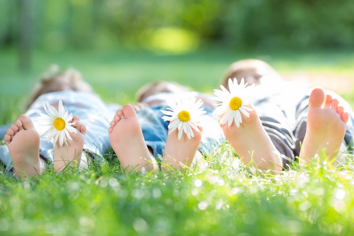 Children's feet with daisies in grass