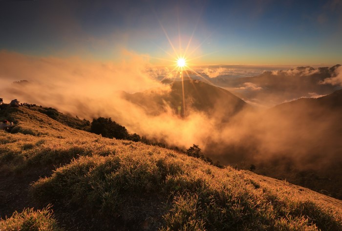 Sunrise over foggy mountains with grass in foreground