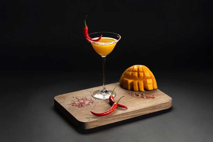 Cocktail with chili pepper and mango on cutting board