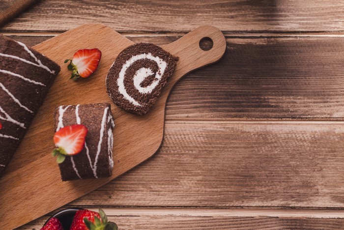4K Swiss roll with strawberries on cutting board