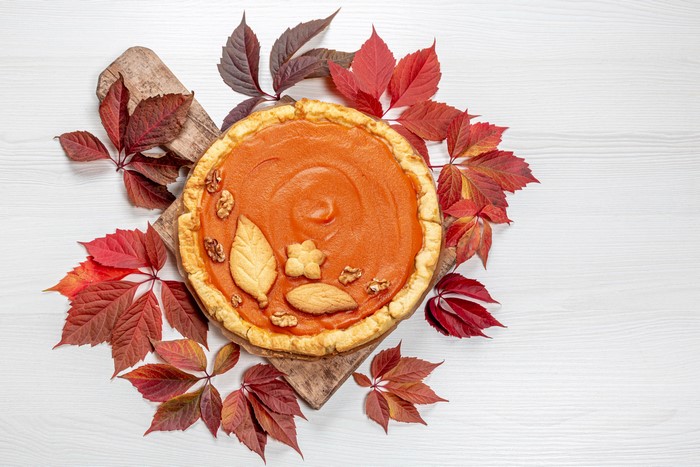 Pumpkin pie with autumn leaves on a cutting board