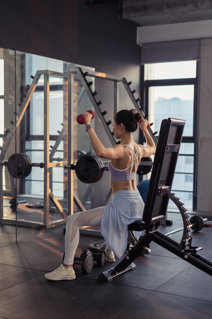 Asian woman doing dumbbell workout in gym