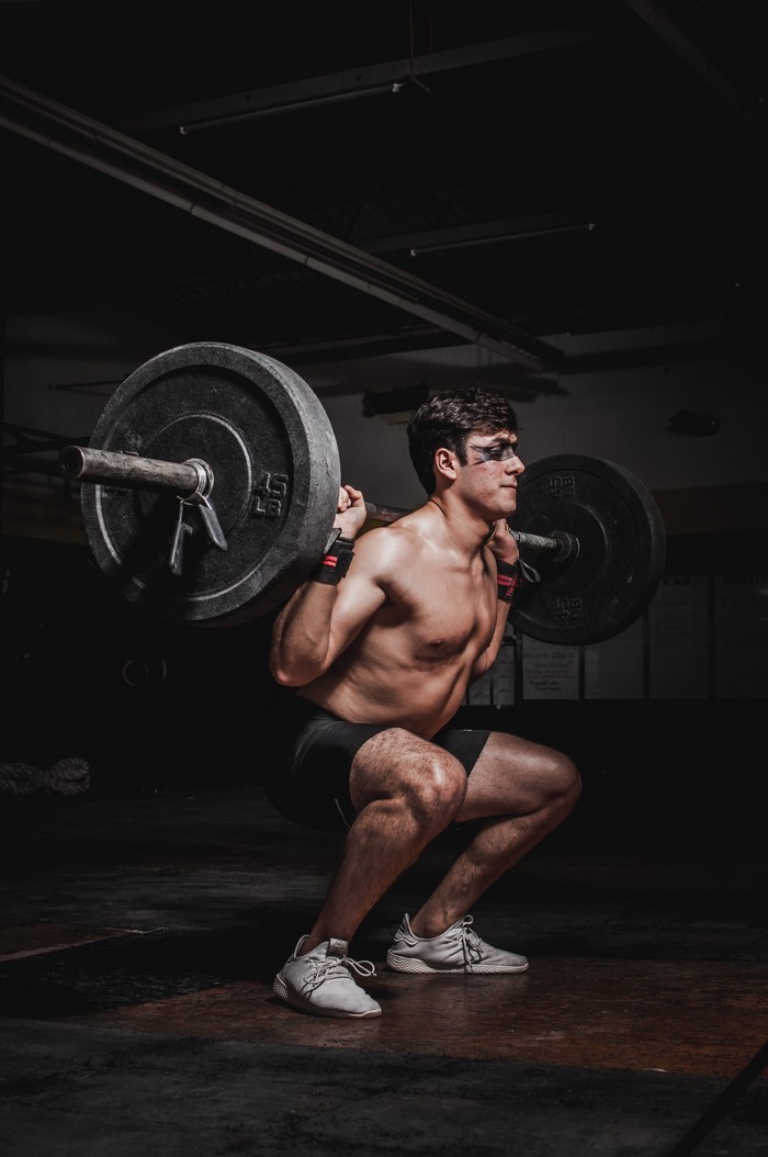 Man performing barbell squats in a gym