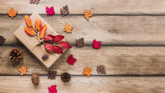 Gift box with autumn leaves and pine cones on wood