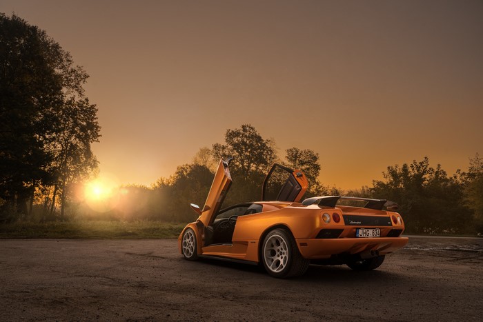 Orange Lamborghini Diablo VT with doors open at sunset